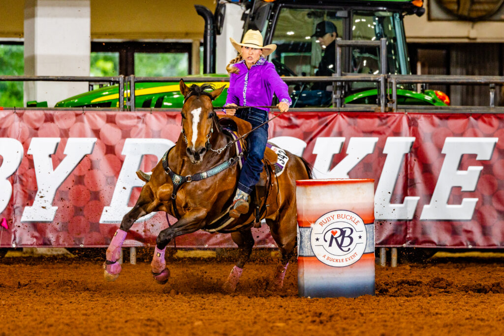 Pink shirt cowgirl turns barrel on horse