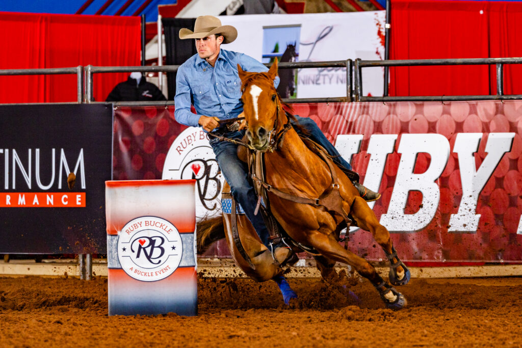Ashton Jones (man) turns a barrel on a red horse