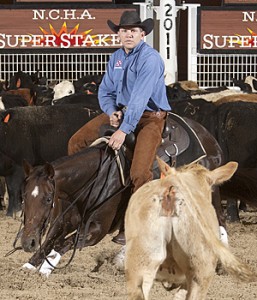 Cutting horse rider in blue shirt and cowboy hat works a light-colored calf in front of the herd at the NCHA Super Stakes