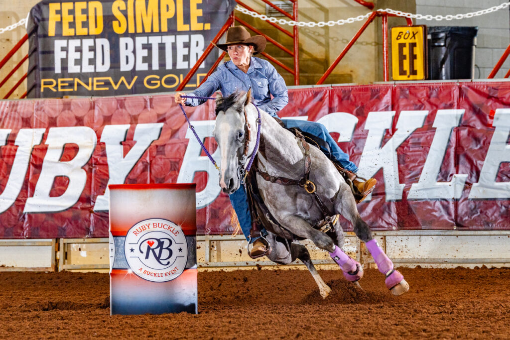 Cassie Morton races around a red barrel on her grey horse