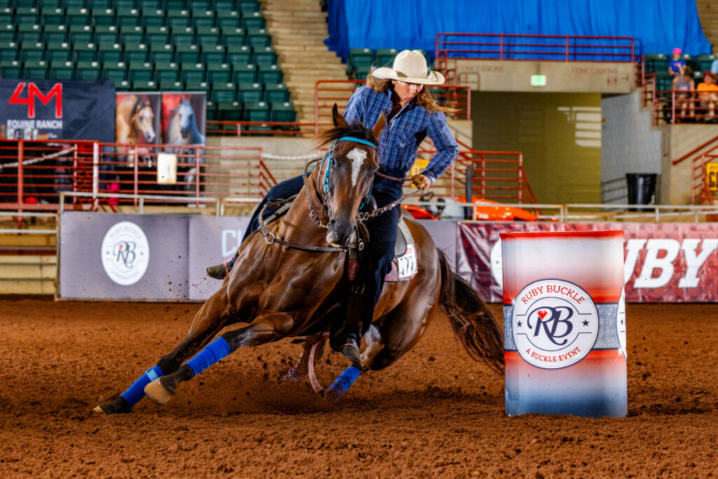 Julie Leao barrel racing in a blue shirt on a bay horse