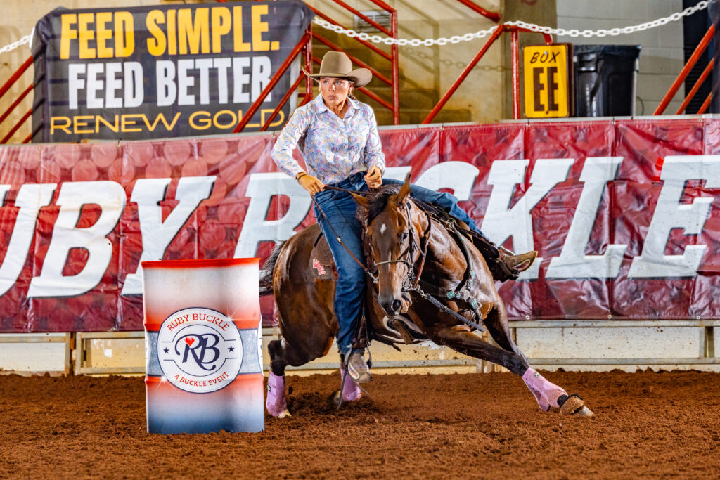 Brecklyn Kuhn turns a red barrel in front of a red banner