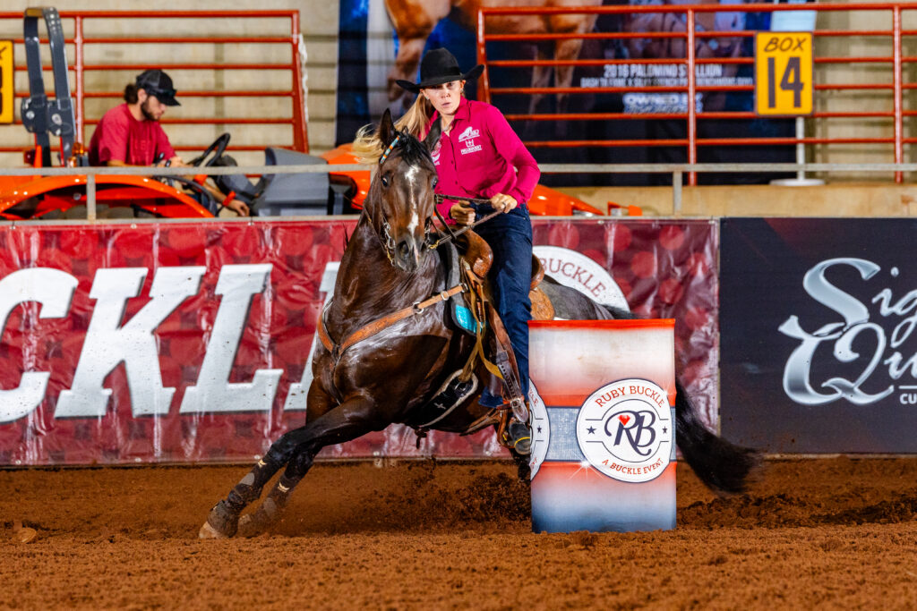 Blonde haired cowgirl turns a Ruby Buckle barrel 
