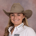 Smiling young woman in a tan cowboy hat and white embroidered team polo posing for a rodeo roster headshot