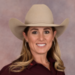 Smiling female rodeo competitor in a tan cowboy hat and maroon shirt posing for a headshot against a red backdrop