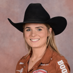 Smiling rodeo competitor in a black cowboy hat and tan sponsor-patched western shirt posing for a headshot