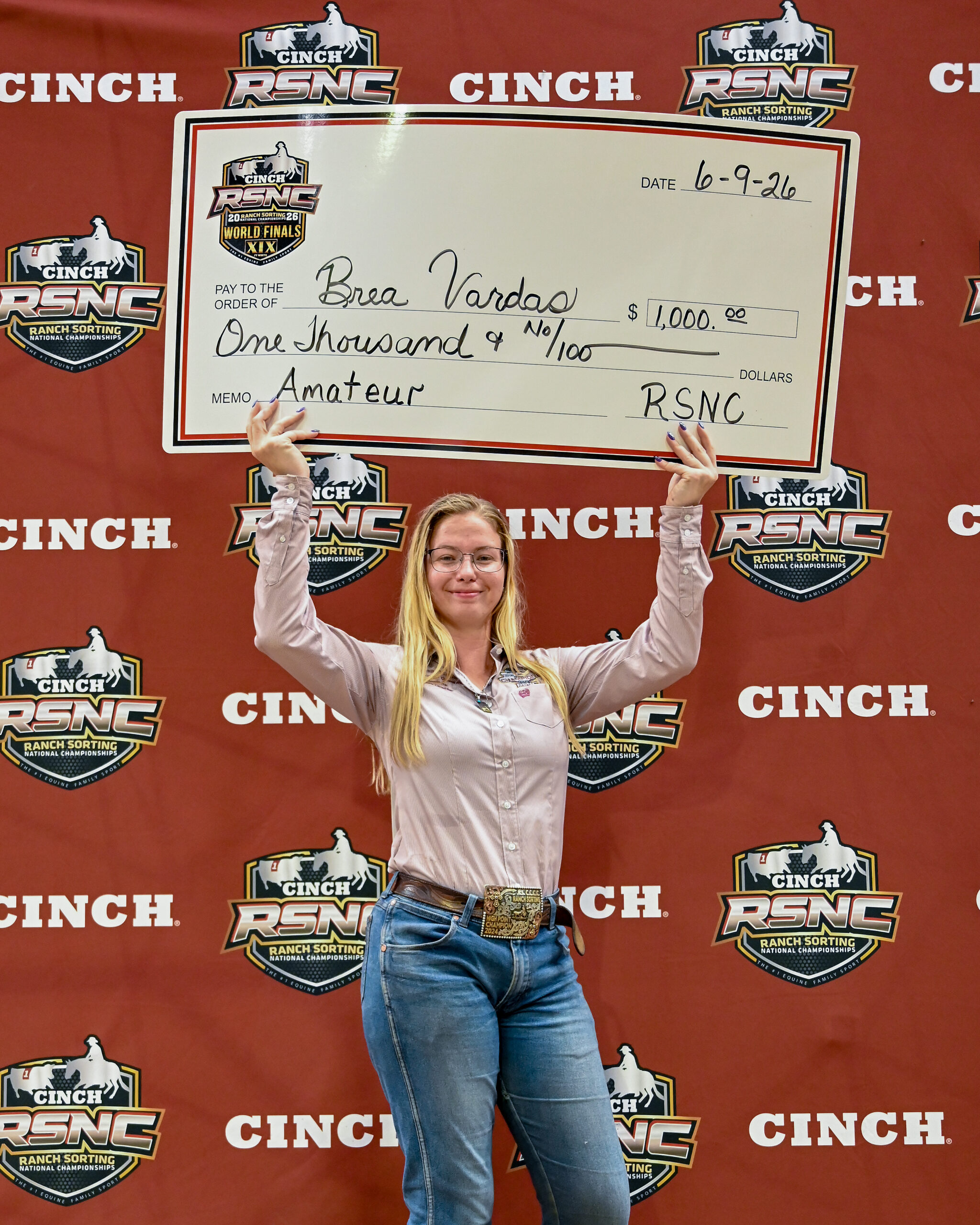 Brea Varday holds an oversized check for $1,000 at the Cinch RSNC World Finals, dated 10-9-26, with an amateur division memo line