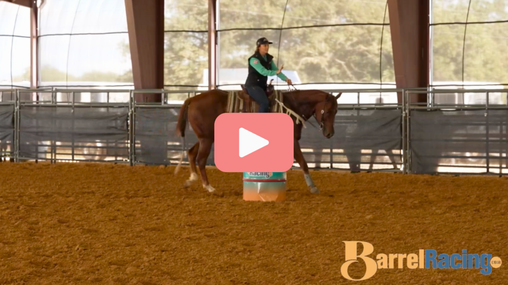 Rider in a teal shirt and black vest works a sorrel horse around an orange barrel in a covered arena, BarrelRacing.com video thumbnail