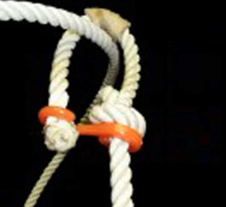 Close-up of a white braided rope honda knot with orange rubber burner against a black background