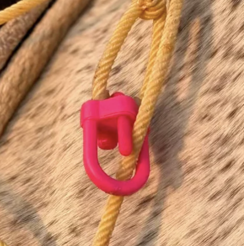 Close-up of a hot pink breakaway rope hondo tied onto a tan roping rope against a speckled cowhide background