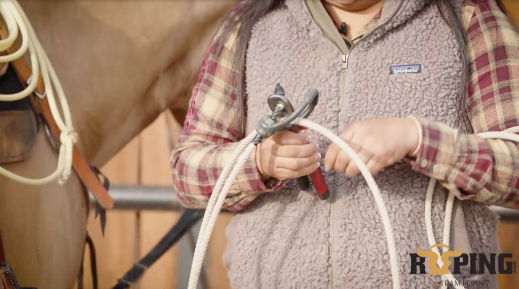 closeup of Danielle Lowman's hand cutting breakaway rope to slide off honda