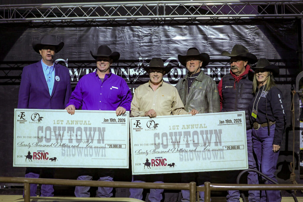 Six people in cowboy hats stand on stage holding two oversized $20,000 Cowtown Showdown checks at a Cinch RSNC event
