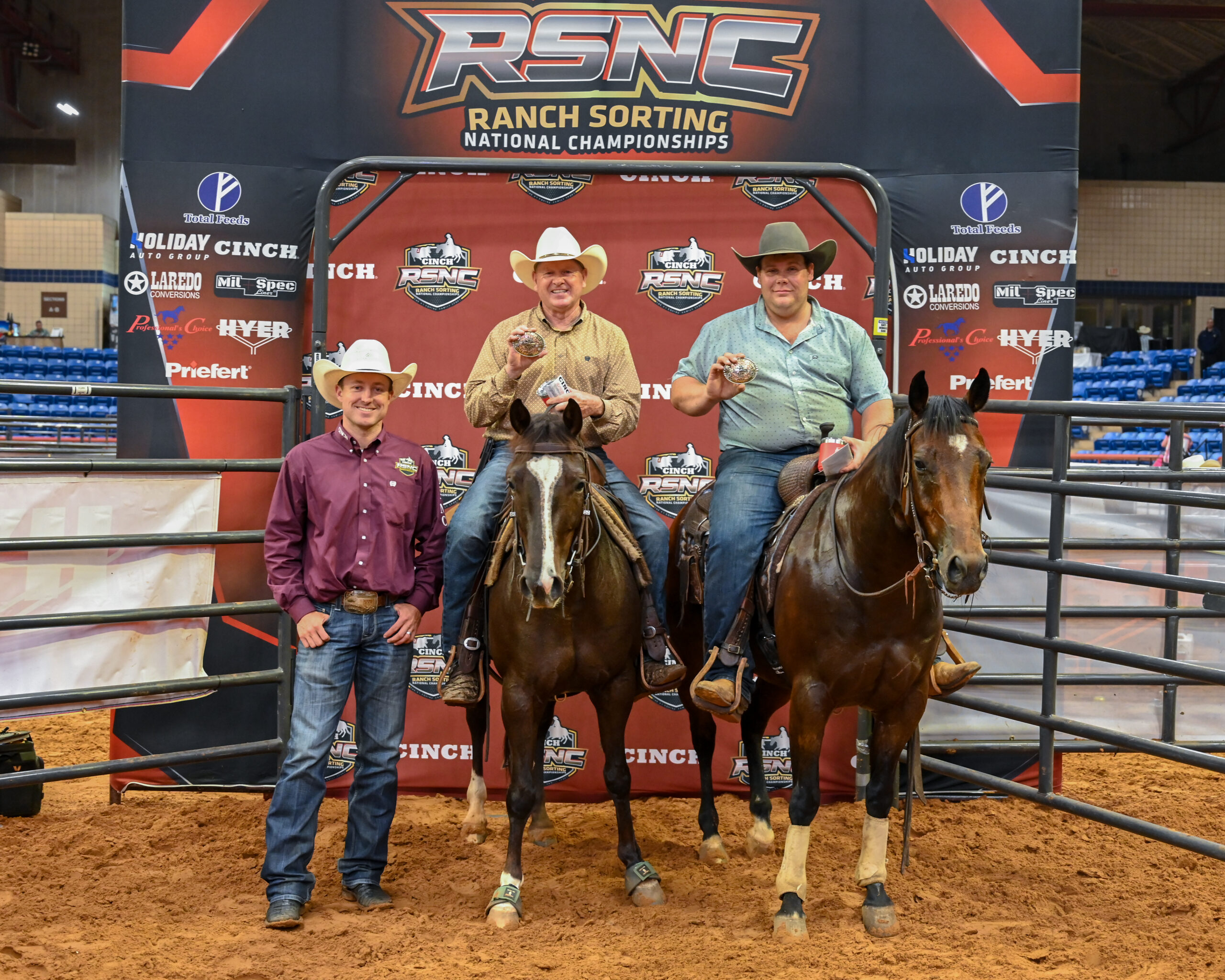 Three mounted competitors and one standing young person pose with horses at the Cinch RSNC Ranch Sorting National Championships
