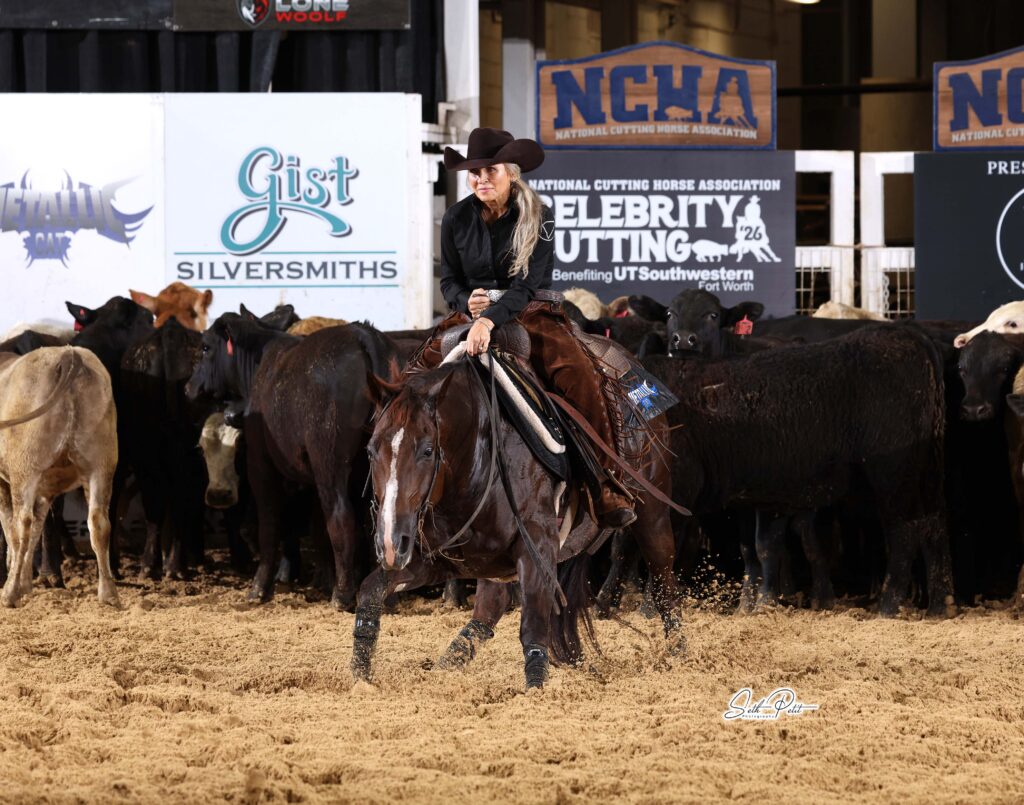 Rider in black hat and shirt works a sorrel cutting horse in front of the herd at an NCHA Celebrity Cutting event
