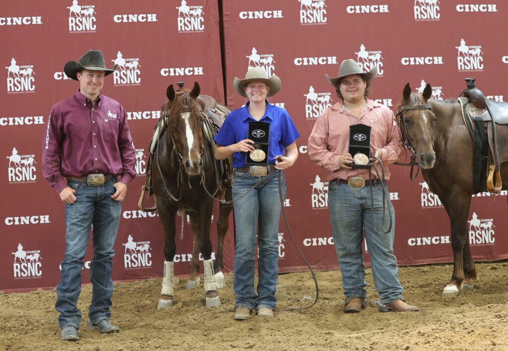Three cowboys and cowgirl winners hold trophy buckles beside their horses in front of a Cinch RSNC backdrop