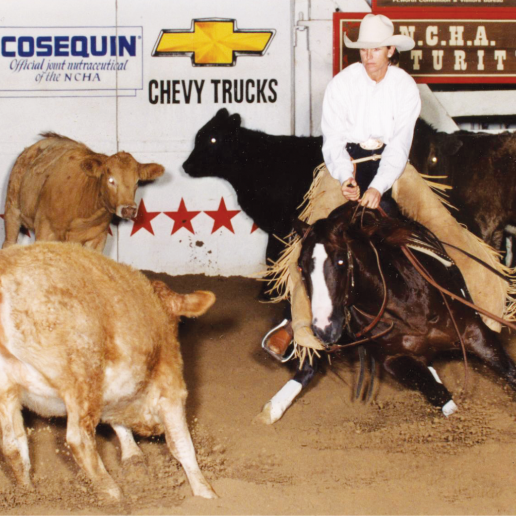 Cutting horse rider in white hat and chaps works a calf in an arena with NCHA and Chevy Trucks banners behind