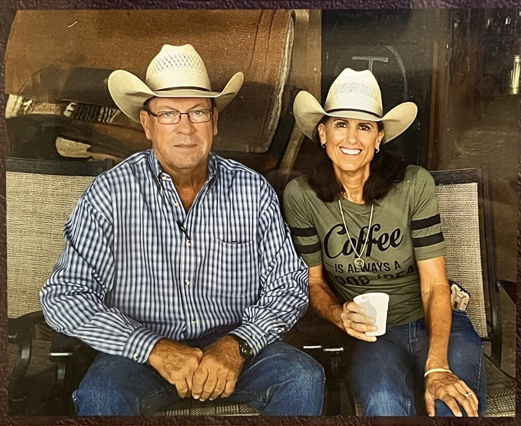 Man and woman in straw cowboy hats sit side by side, she smiles holding a foam cup in a "Coffee" tee