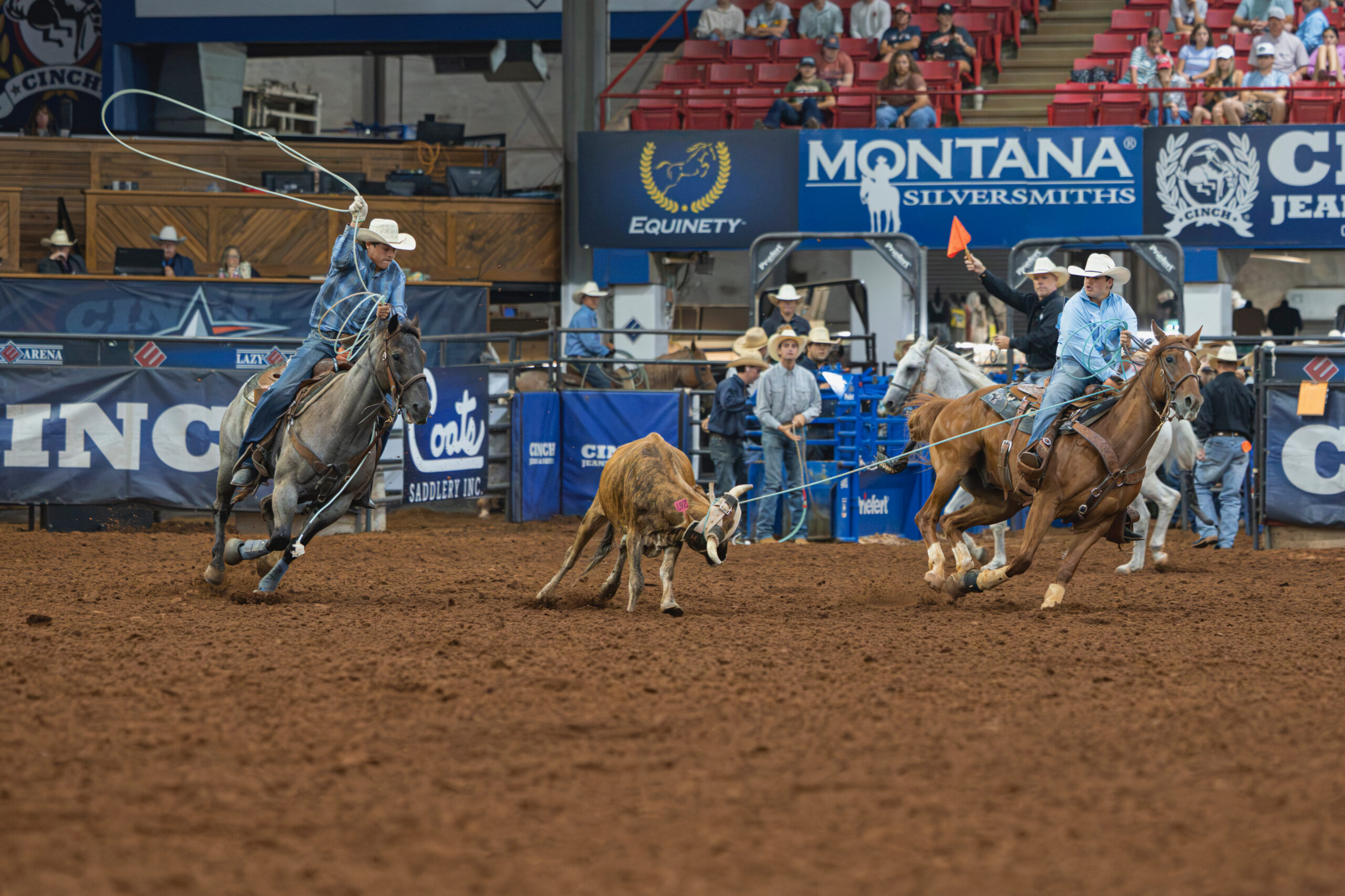 Team ropers work a steer during competition at an indoor rodeo arena sponsored by Montana Silversmiths