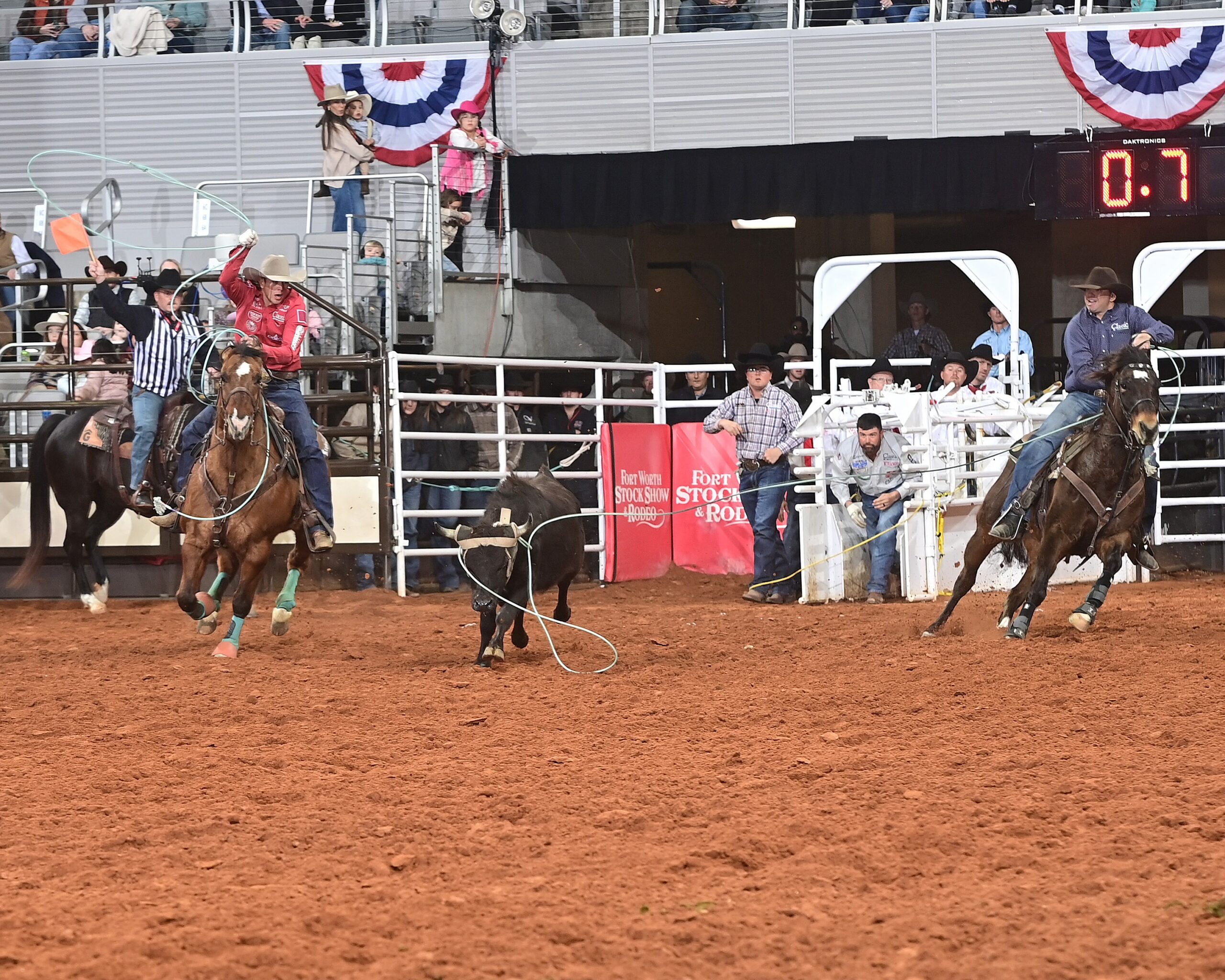 Team ropers compete during a rodeo event at Fort Worth Stock Show & Rodeo, with one rider roping a steer while a hazer approaches on horseback