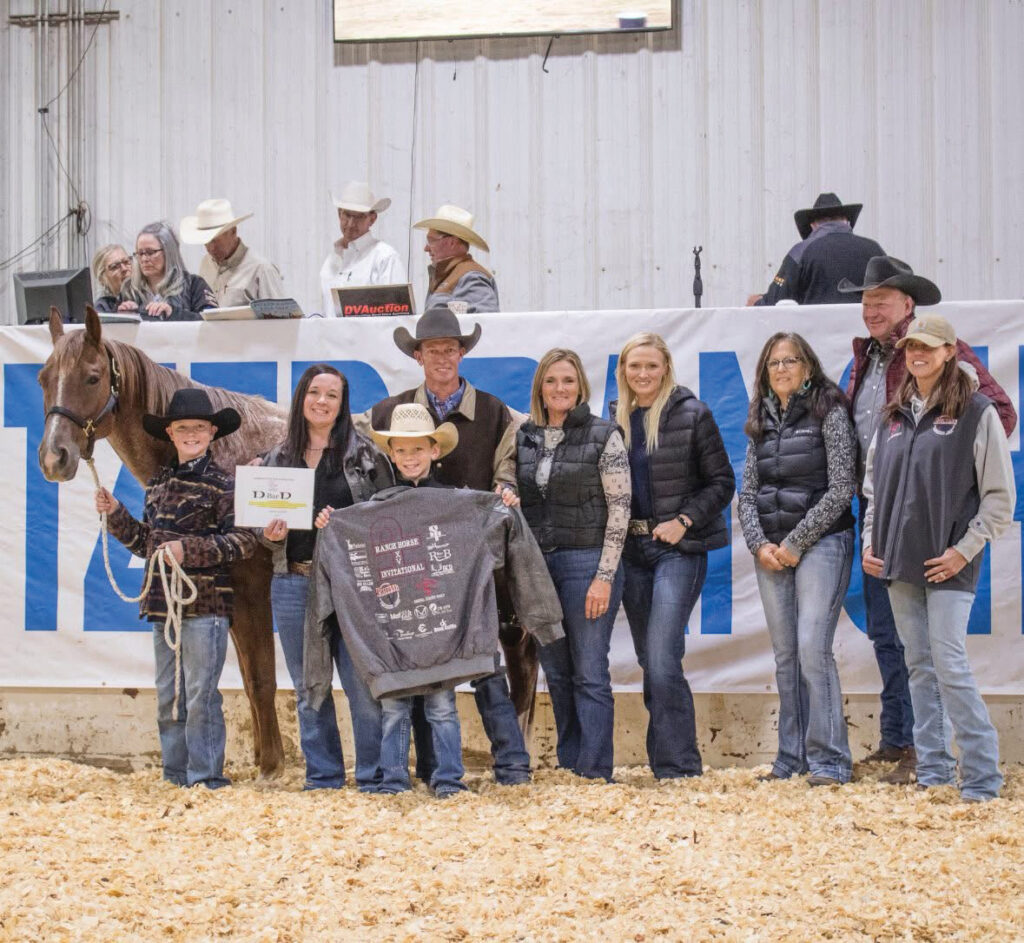 Young exhibitor with horse and handler receive award at indoor rodeo arena with family and officials present