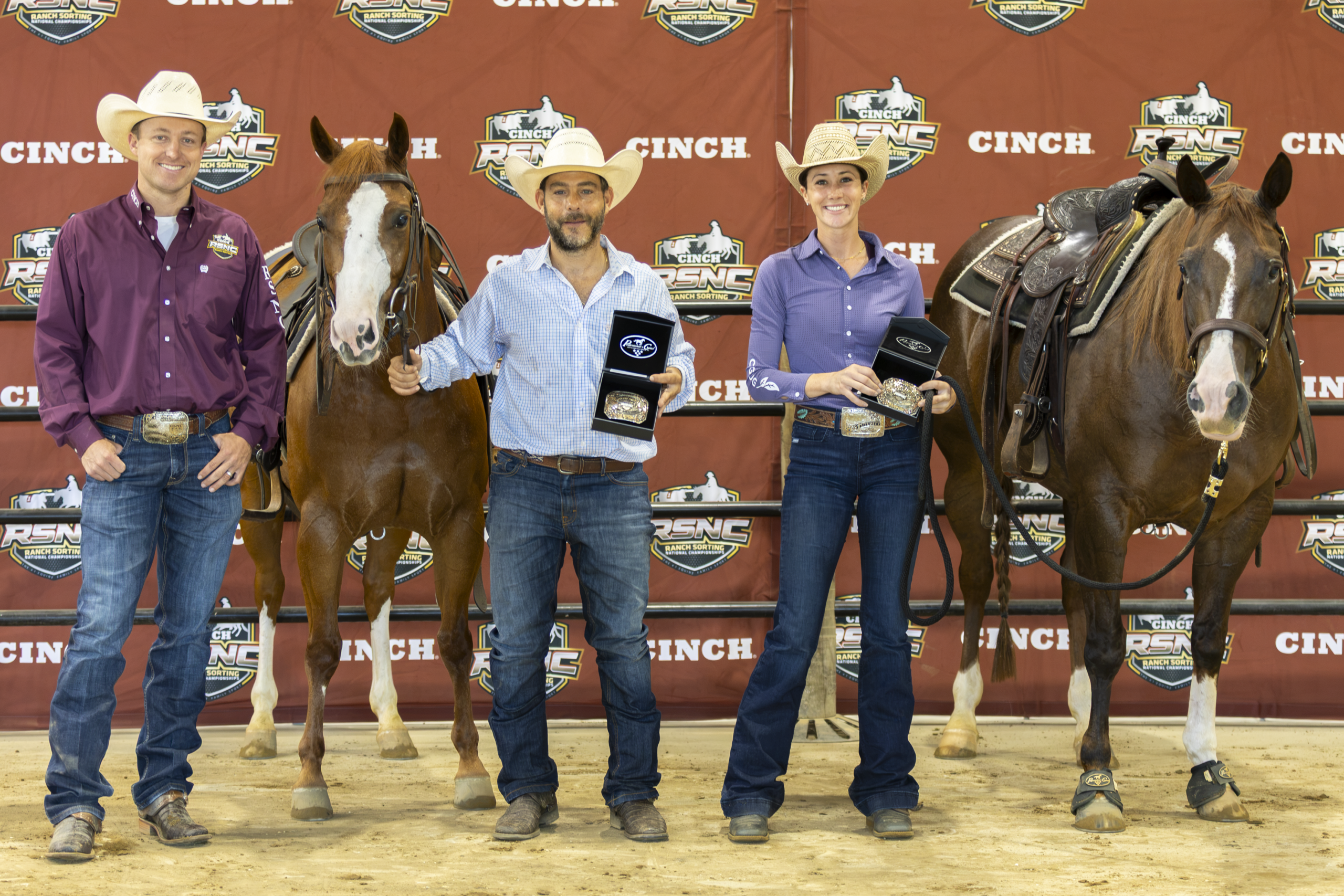 Five people stand with two horses in front of a Cinch-branded backdrop, holding awards at a rodeo event