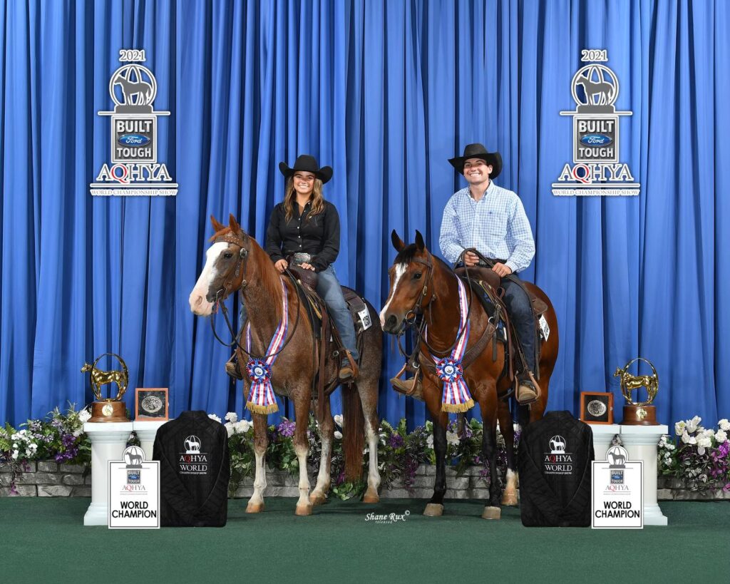 Two mounted riders in cowboy hats pose with championship trophies, coolers and neck ribbons at the 2021 AQHYA World Championship Show