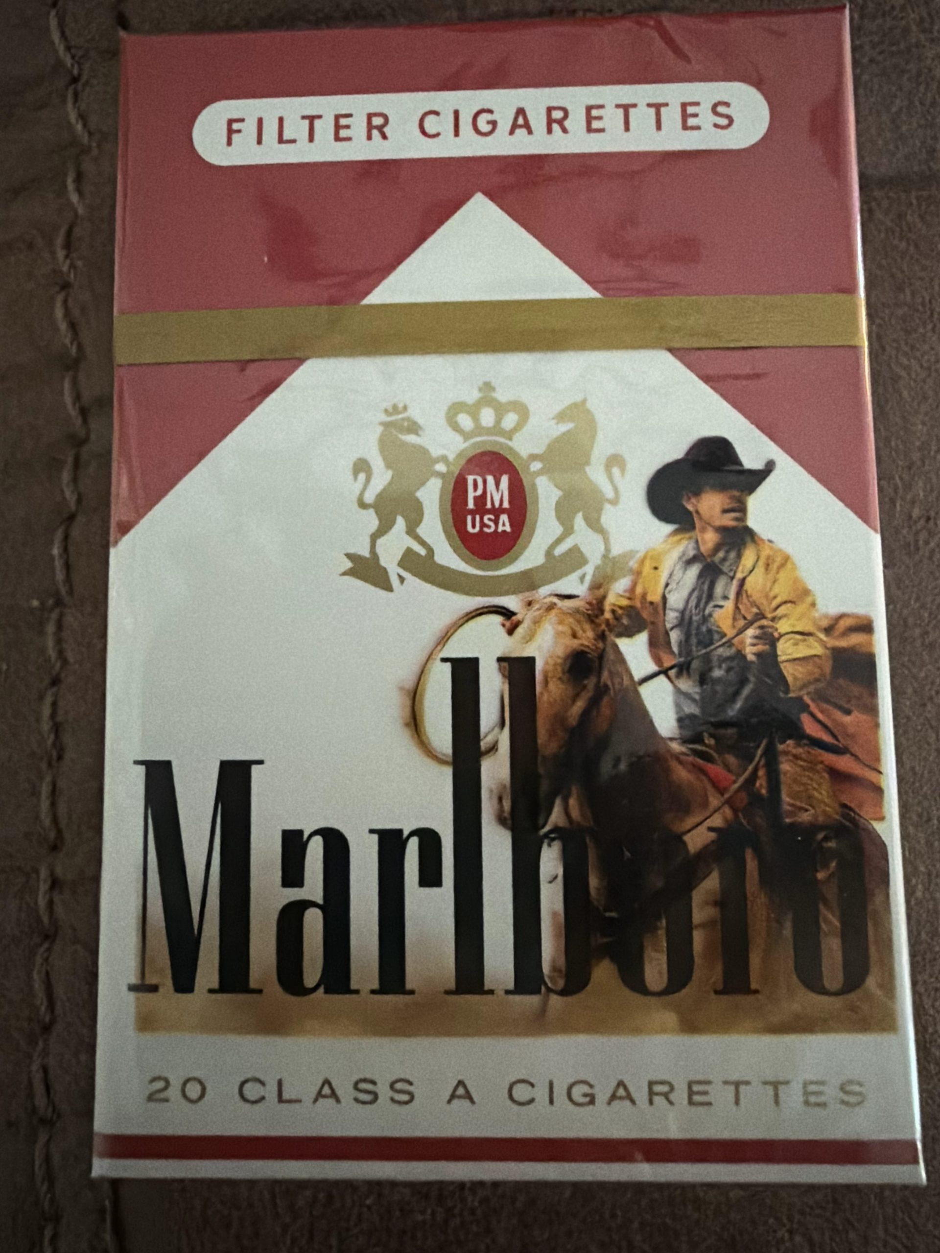 Vintage Marlboro cigarette pack featuring a cowboy on horseback in Western attire with a gold crown emblem above